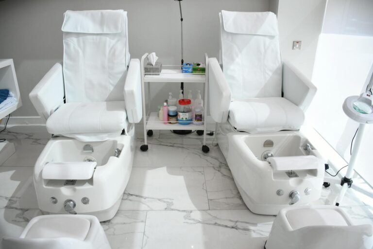 Elegant white spa chairs ready for pampering treatments in Abu Dhabi salon.